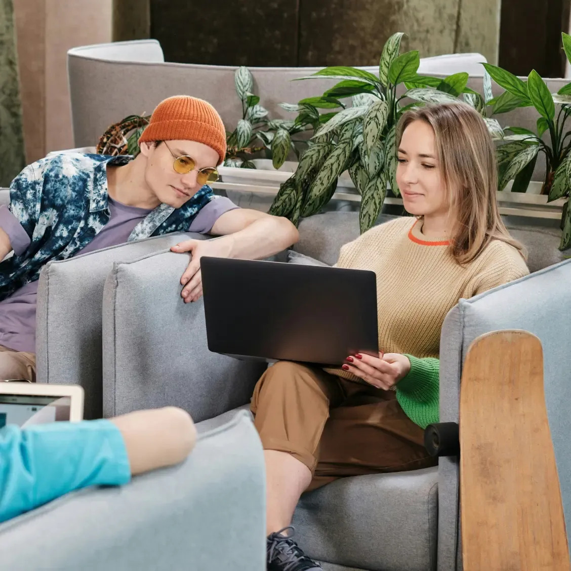 Deux employés assis sur un divan consultent ensemble leurs avantages sur un ordinateur portable.