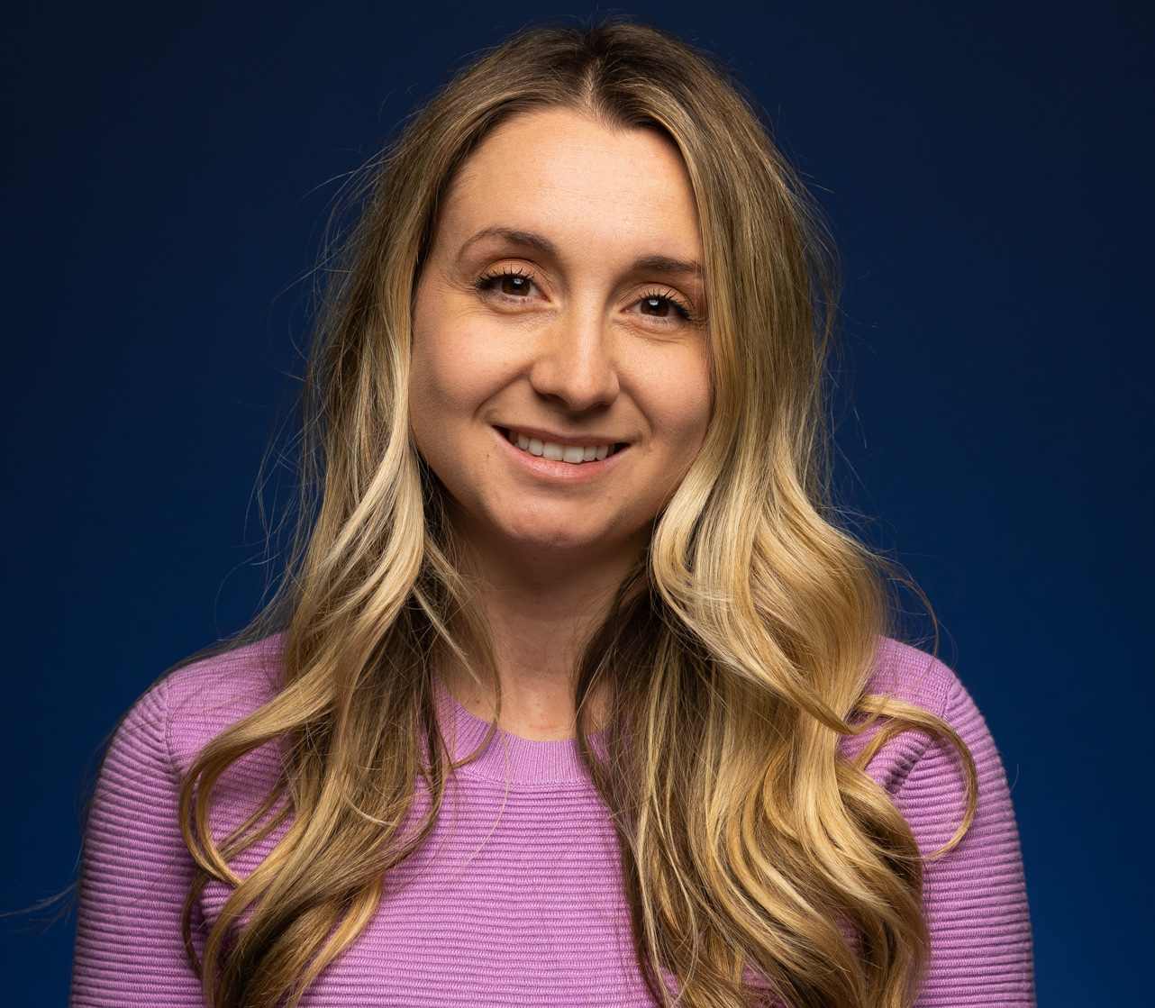 Emilie St-Aubin pose devant un fond bleu fonce.